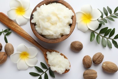 Photo of Shea butter, nuts, plumeria flowers and leaves on white background, flat lay