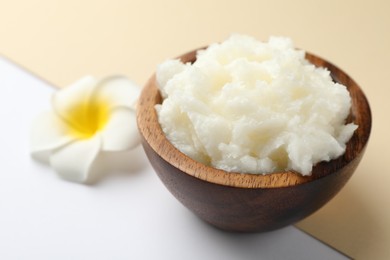 Photo of Shea butter and plumeria flower on color background, closeup