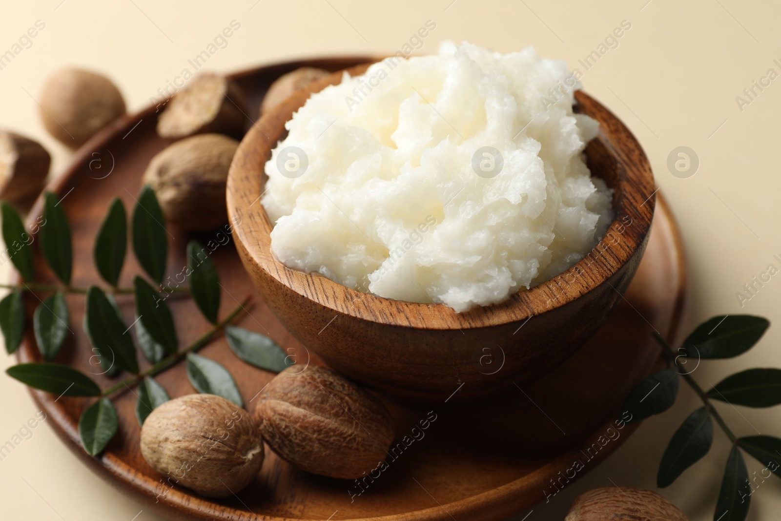 She butter, nuts and leaves on beige background, closeup Photo of She butter, nuts and leaves on beige background, closeup