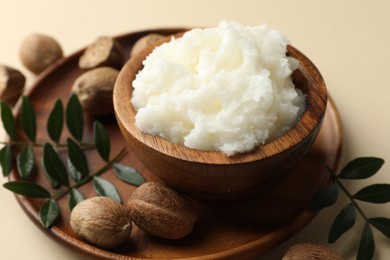 Photo of She butter, nuts and leaves on beige background, closeup