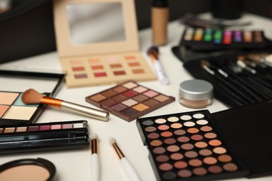 Photo of Different makeup products and brushes on dressing table indoors, closeup