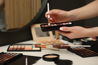 Photo of Woman with brush and eyeshadow palette at dressing table, closeup