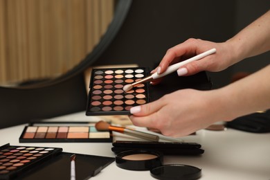 Photo of Woman with brush and eyeshadow palette at dressing table, closeup