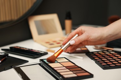 Photo of Woman with brush and correcting concealer palette at dressing table, closeup