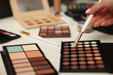 Photo of Woman with brush and eyeshadow palette at dressing table, closeup