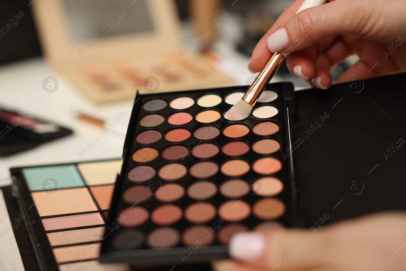 Woman with brush and eyeshadow palette at dressing table, closeup Photo of Woman with brush and eyeshadow palette at dressing table, closeup