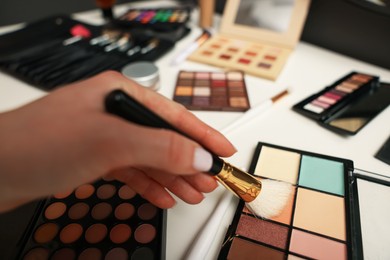 Photo of Woman with brush and correcting concealer palette at dressing table, closeup