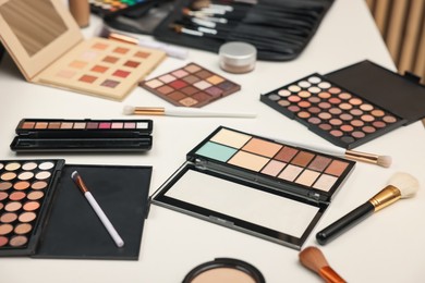 Photo of Different makeup products and brushes on dressing table, closeup
