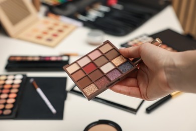 Photo of Woman with eyeshadow palette at dressing table, closeup