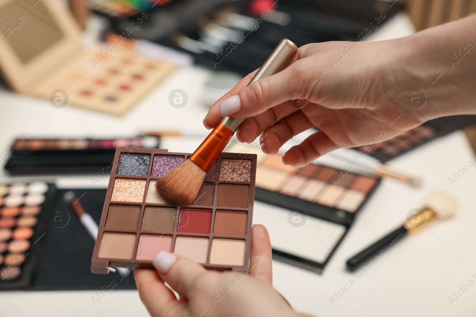 Woman with brush and eyeshadow palette at dressing table, closeup Photo of Woman with brush and eyeshadow palette at dressing table, closeup