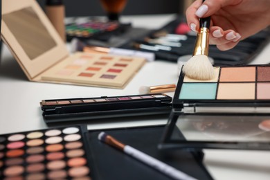 Photo of Woman with brush and correcting concealer palette at dressing table, closeup