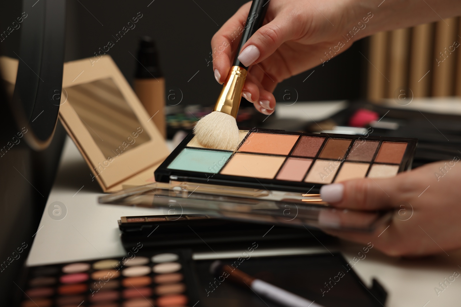 Woman with brush and correcting concealer palette at dressing table, closeup Photo of Woman with brush and correcting concealer palette at dressing table, closeup