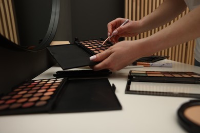 Photo of Woman with brush and eyeshadow palette at dressing table, closeup