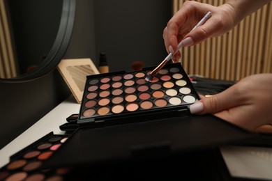Photo of Woman with brush and eyeshadow palette at dressing table, closeup