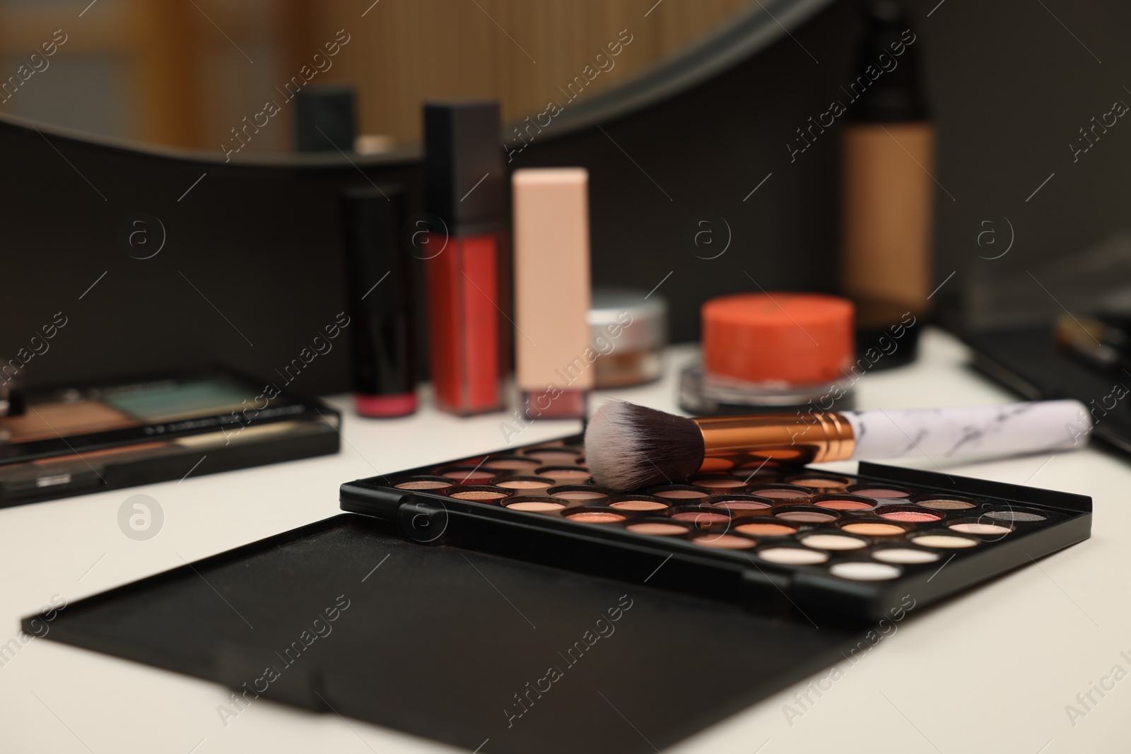 Different makeup products and brush on dressing table indoors, closeup Photo of Different makeup products and brush on dressing table indoors, closeup