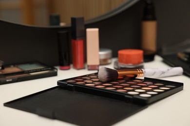Photo of Different makeup products and brush on dressing table indoors, closeup