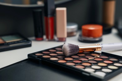 Photo of Different makeup products and brush on dressing table indoors, closeup