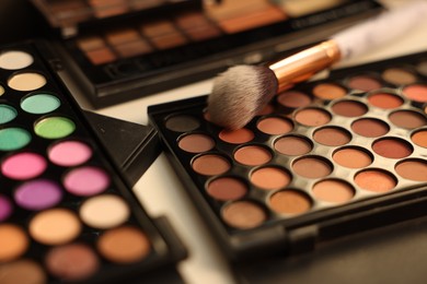 Photo of Different makeup products and brush on dressing table, closeup