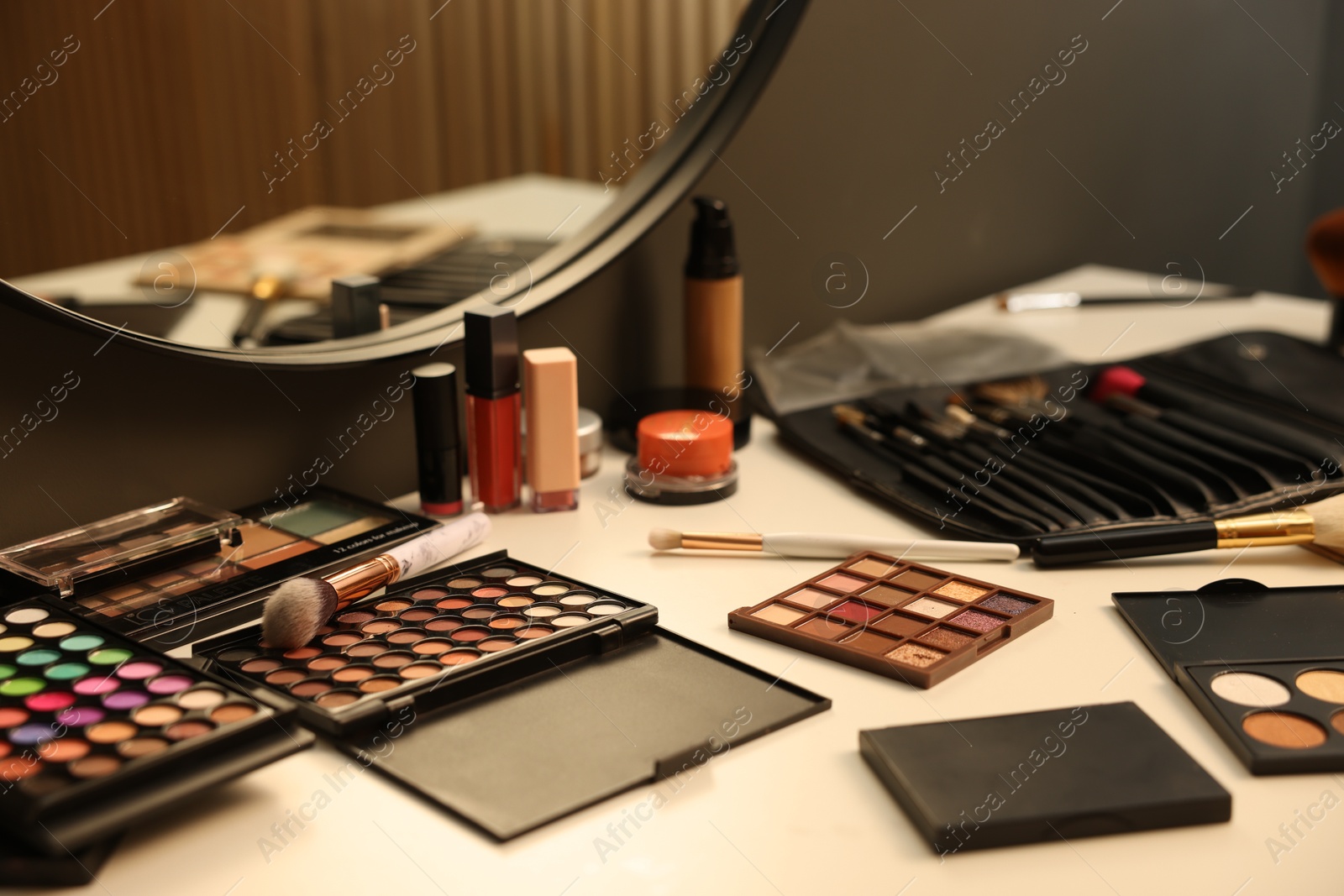 Photo of Different makeup products and brushes on dressing table indoors, closeup