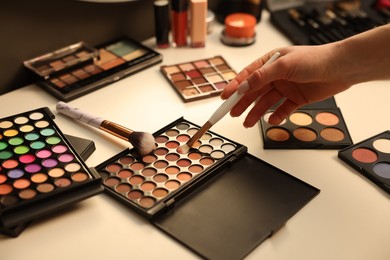 Photo of Woman with brush and eyeshadow palette at dressing table, closeup