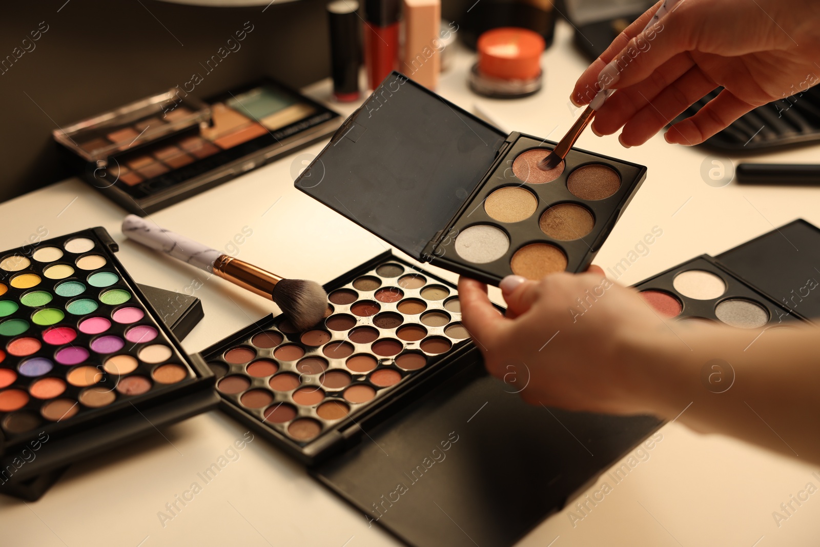 Photo of Woman with brush and eyeshadow palette at dressing table, closeup