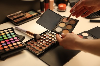 Photo of Woman with brush and eyeshadow palette at dressing table, closeup