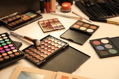 Photo of Different makeup products and brushes on dressing table, closeup