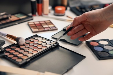 Photo of Woman with brush and eyeshadow palette at dressing table, closeup
