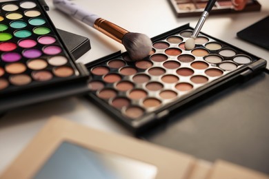 Photo of Different makeup products and brushes on dressing table, closeup