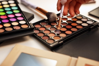 Photo of Woman with brush and eyeshadow palette at dressing table, closeup