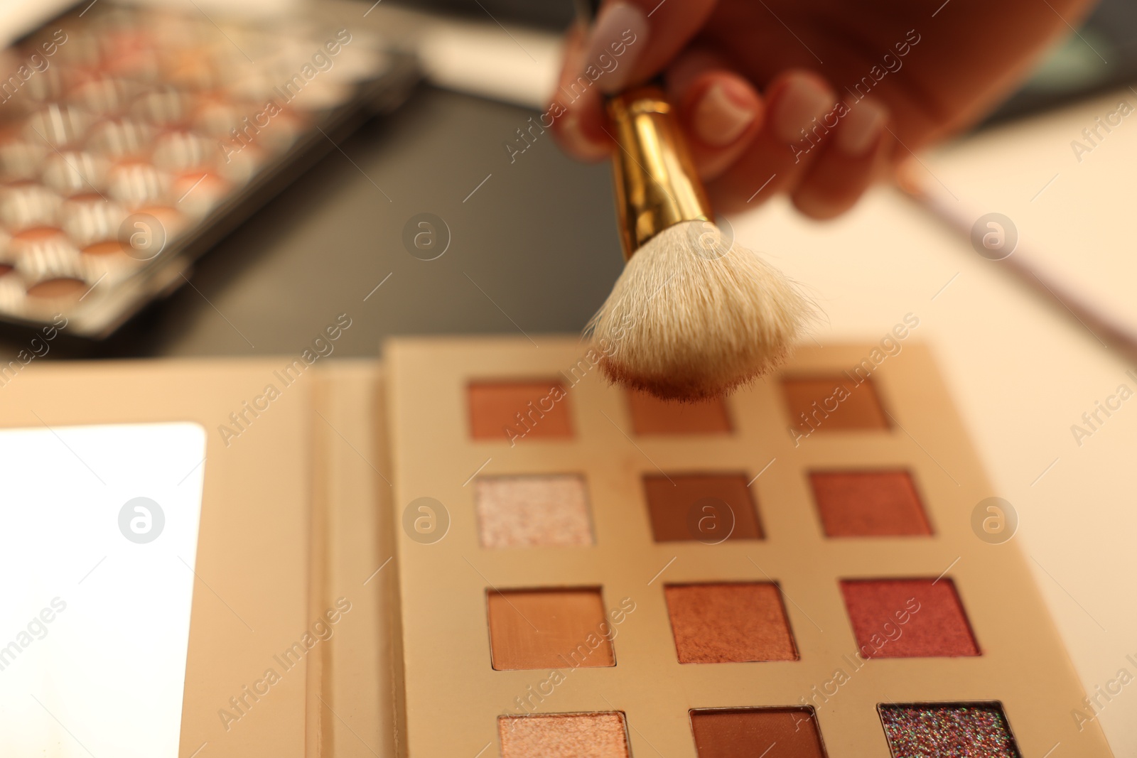 Photo of Woman with brush and eyeshadow palette at dressing table, closeup
