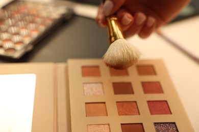 Photo of Woman with brush and eyeshadow palette at dressing table, closeup