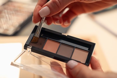 Photo of Woman with brush and eyeshadow palette at dressing table, closeup