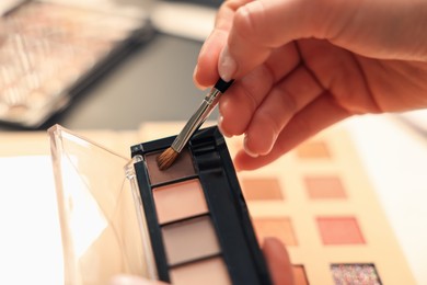 Photo of Woman with brush and eyeshadow palette at dressing table, closeup