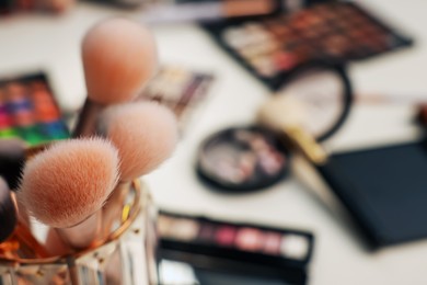 Photo of Different makeup products and brushes on dressing table, closeup. Space for text