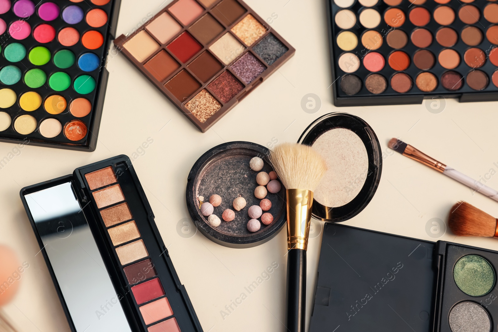 Photo of Different makeup products and brushes on dressing table, flat lay