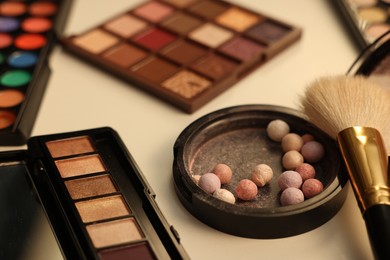 Photo of Different makeup products and brush on dressing table, closeup