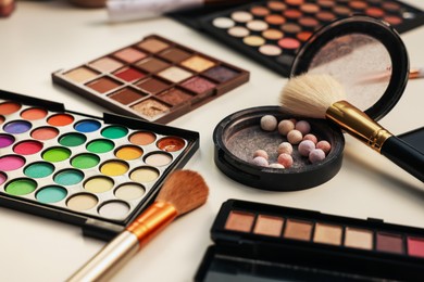 Photo of Different makeup products and brushes on dressing table, closeup
