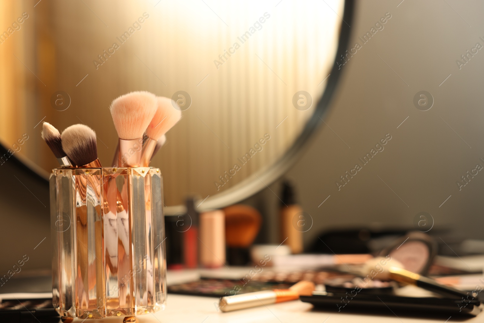 Brushes and cosmetic products on dressing table indoors, closeup Photo of Brushes and cosmetic products on dressing table indoors, closeup