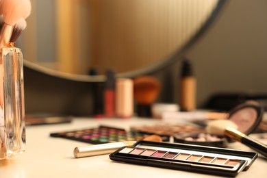 Photo of Different makeup products and brushes on dressing table indoors, closeup