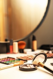 Photo of Different makeup products and brushes on dressing table indoors, closeup