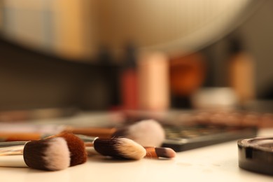 Photo of Brushes and cosmetic products on dressing table indoors, closeup