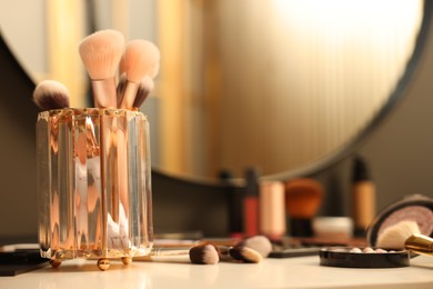 Photo of Different makeup products and brushes on dressing table indoors, closeup