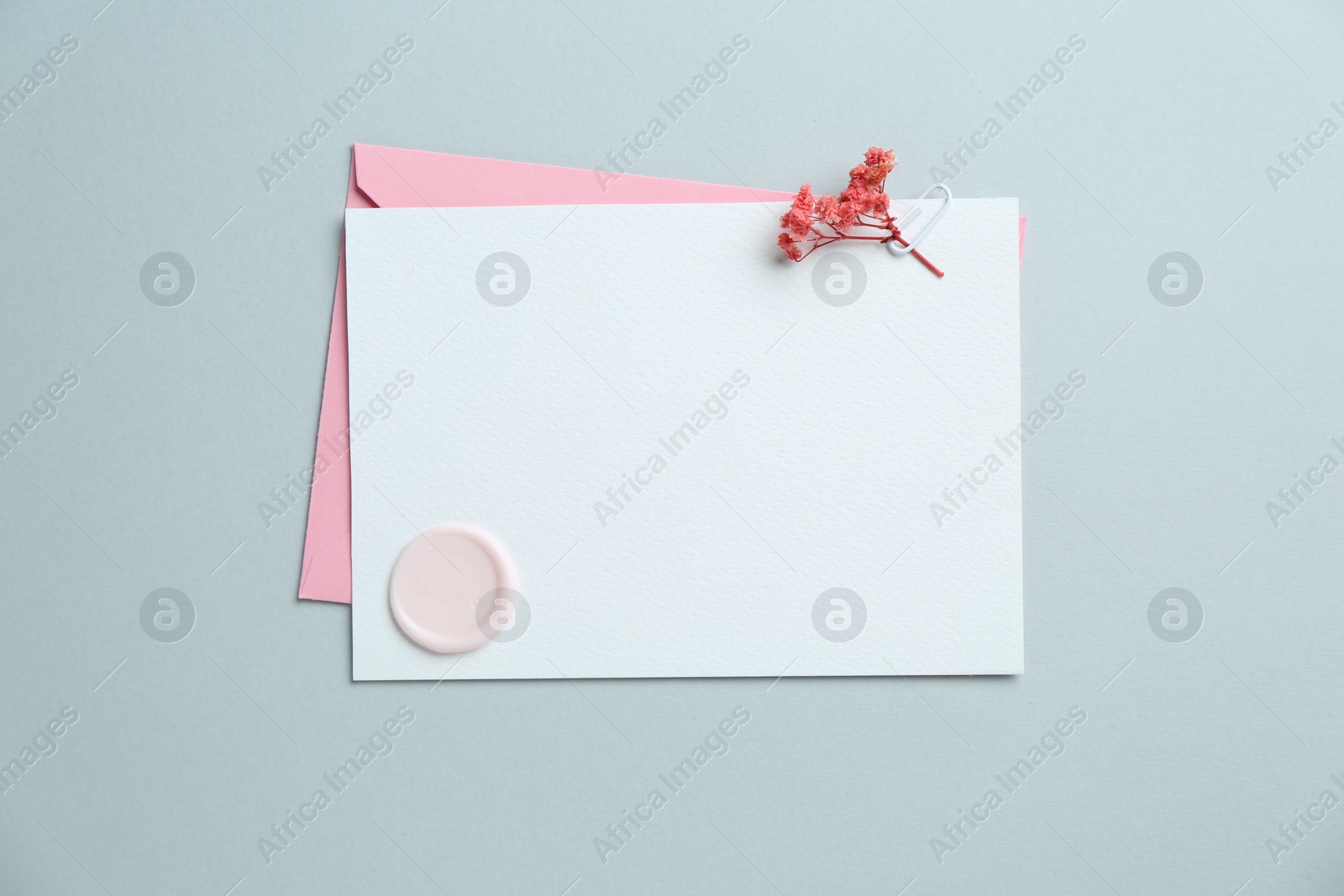 Blank invitation card with wax seal, flowers and envelope on grey background, top view. Space for design Photo of Blank invitation card with wax seal, flowers and envelope on grey background, top view. Space for design