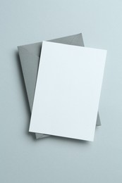 Photo of Blank invitation card and envelope on grey background, top view. Space for design