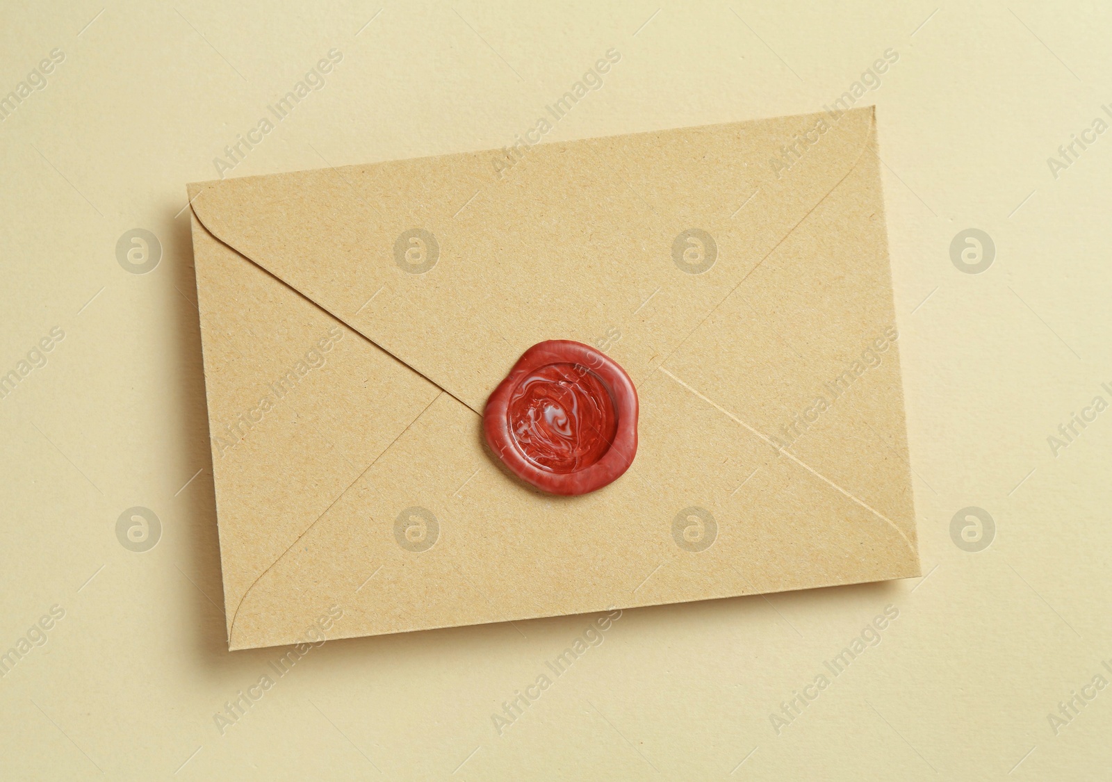 Beautiful invitation envelope with wax seal on beige background, top view Photo of Beautiful invitation envelope with wax seal on beige background, top view