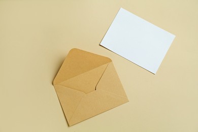 Photo of Blank invitation card and envelope on beige background, flat lay. Space for design