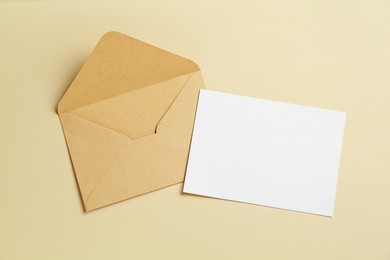 Photo of Blank invitation card and envelope on beige background, flat lay. Space for design