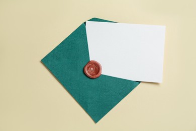 Photo of Blank invitation card and envelope on beige background, top view. Space for design