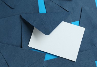 Photo of Blank invitation card and envelopes on light blue background, flat lay. Space for design